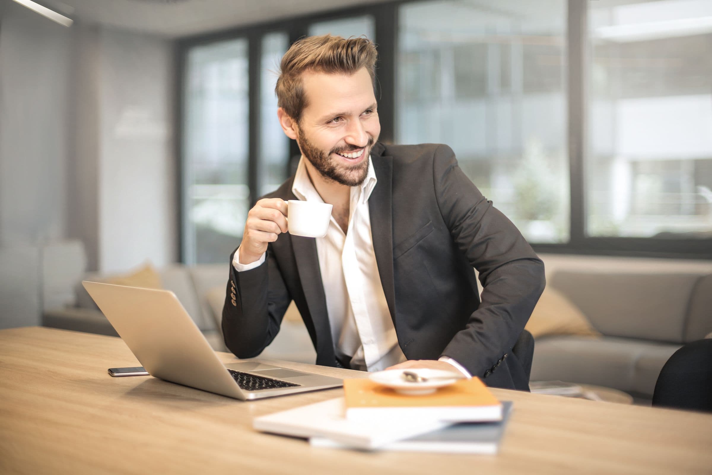 Selbstständiger mit Kaffeetasse am Laptop
